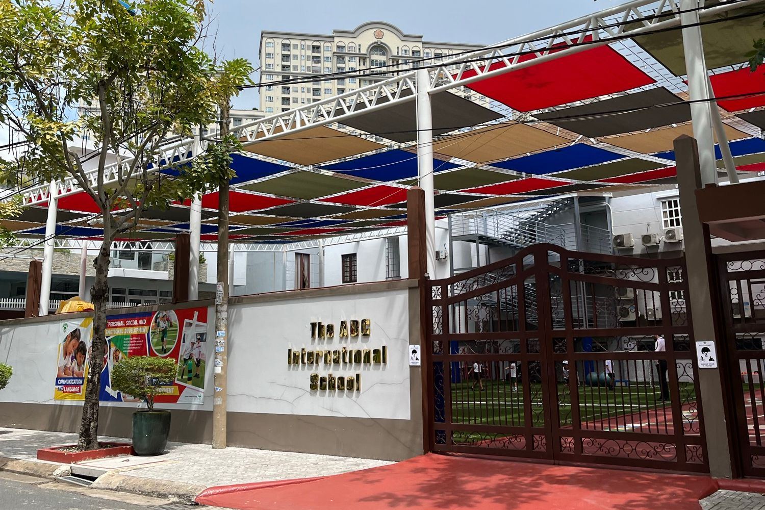 색색의 그늘막 아래 학교 이름 간판이 붙은 ABCIS 국제학교 초등 캠퍼스 정문