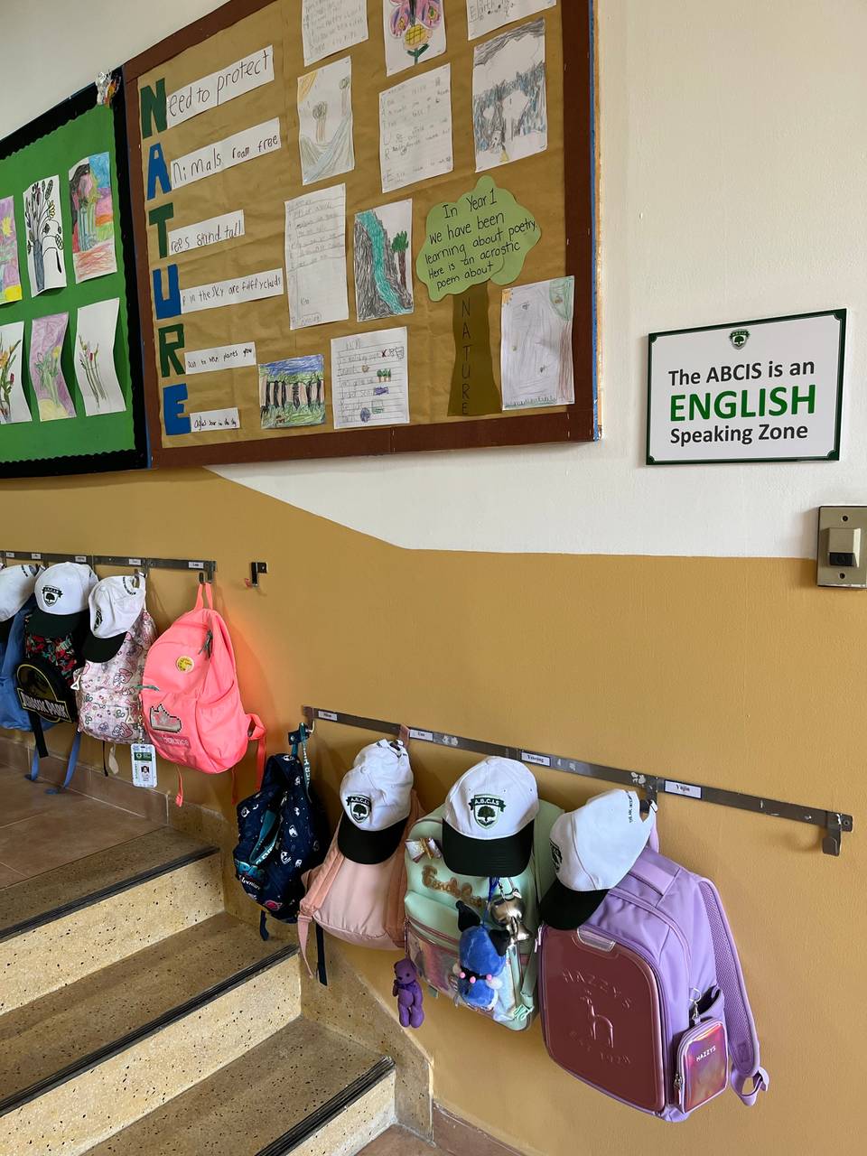 English Speaking Zone 안내와 가방 · 모자가 걸린 계단 벽