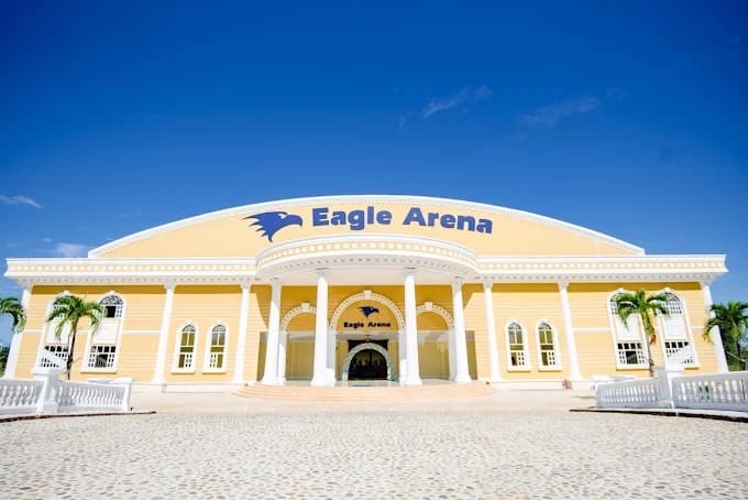 'Eagle Arena'라고 적힌 노란색 체육관 건물 정면과 야자수