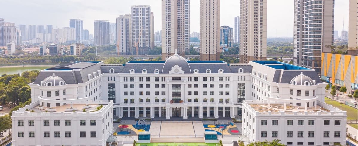 위에서 내려다본 흰색 학교 건물과 가운데 마당, 뒤편의 고층 아파트