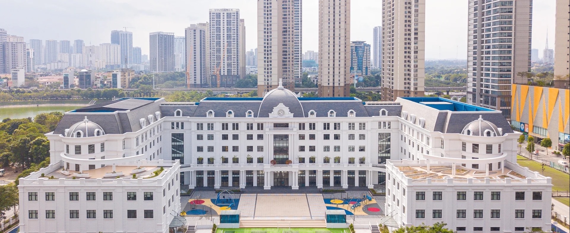 위에서 내려다본 흰색 학교 건물과 가운데 마당, 뒤편의 고층 아파트