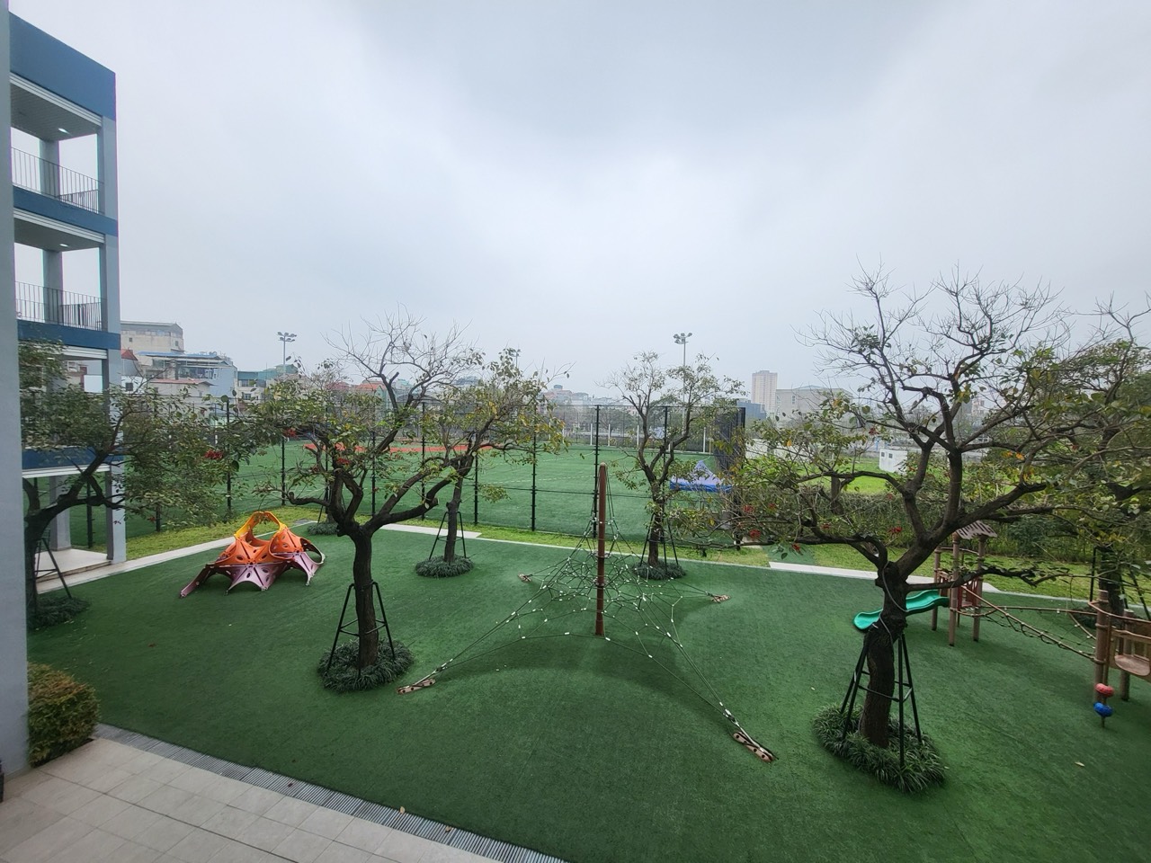 인공잔디 위에 나무와 놀이 기구가 있는 놀이터