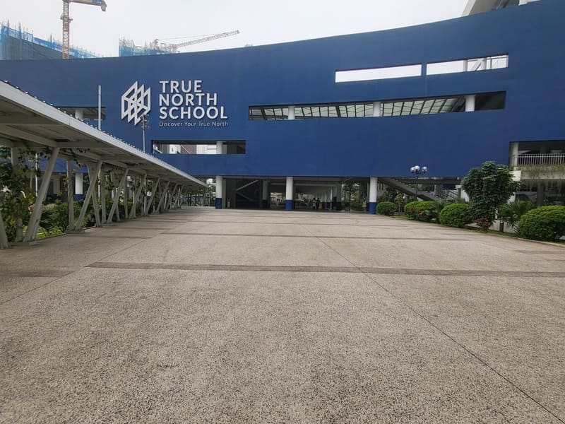 TNIS 국제학교의 파란 본관 외벽에 붙은 True North School 로고와 앞마당
