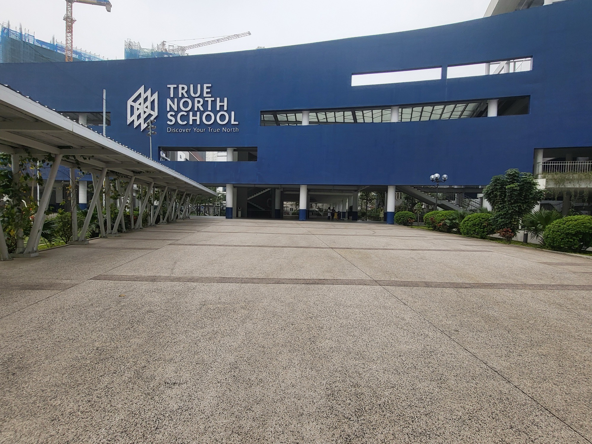TNIS 국제학교의 파란 본관 외벽에 붙은 True North School 로고와 앞마당